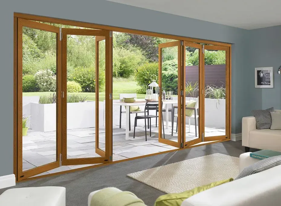 Warm timber bifold doors opening from a living room onto a paved garden terrace